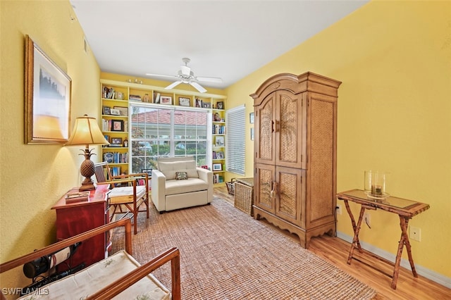 living area featuring ceiling fan, built in features, and hardwood / wood-style floors