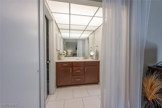 bathroom with a drop ceiling, tile patterned floors, and vanity