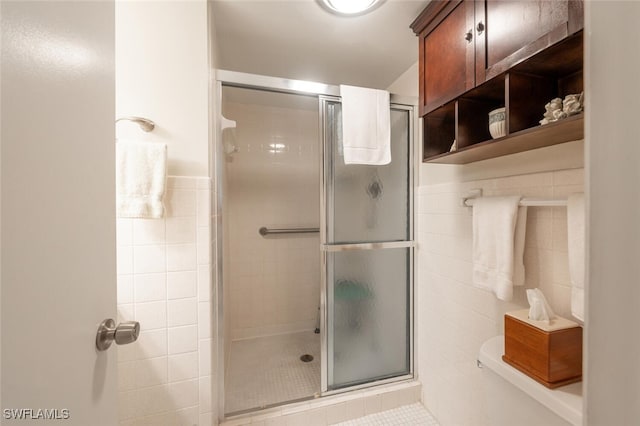 bathroom featuring tile walls, tile patterned flooring, and a shower with shower door