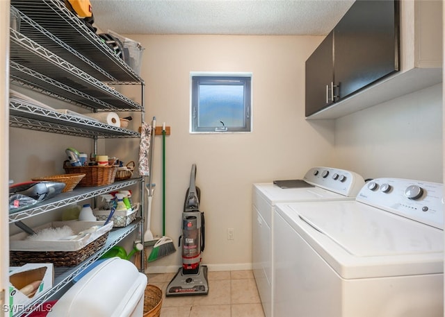 washroom with cabinets, separate washer and dryer, light tile patterned floors, and a textured ceiling