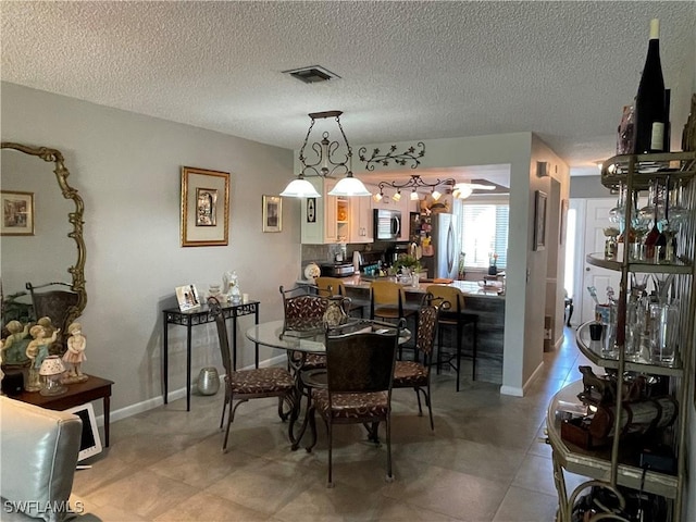 dining space with light tile patterned floors, baseboards, visible vents, and a textured ceiling