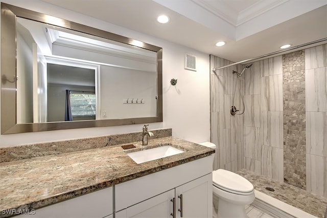 bathroom with crown molding, tiled shower, vanity, and toilet