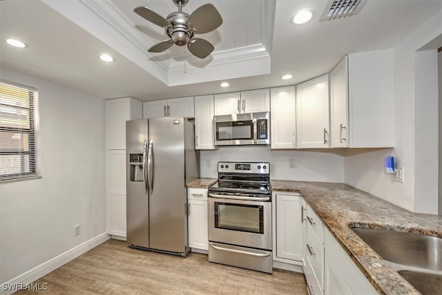 kitchen with ceiling fan, white cabinets, appliances with stainless steel finishes, and a raised ceiling