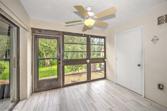 unfurnished sunroom featuring ceiling fan