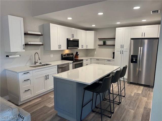 kitchen with a kitchen island, white cabinetry, sink, and appliances with stainless steel finishes