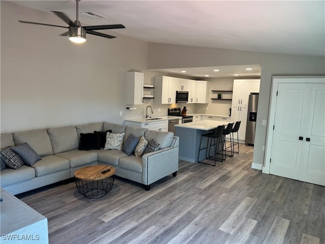 living room with ceiling fan, sink, vaulted ceiling, and hardwood / wood-style flooring