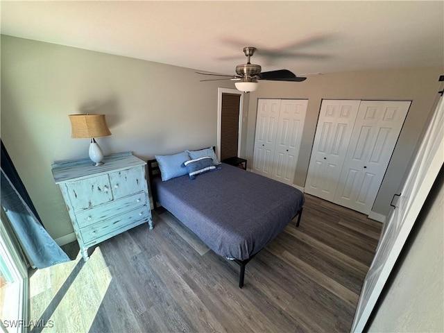 bedroom with two closets, ceiling fan, and dark wood-type flooring