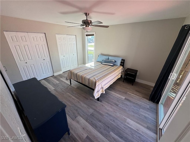 bedroom featuring dark hardwood / wood-style floors, ceiling fan, and multiple closets