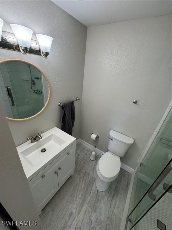 bathroom featuring an enclosed shower, vanity, and toilet