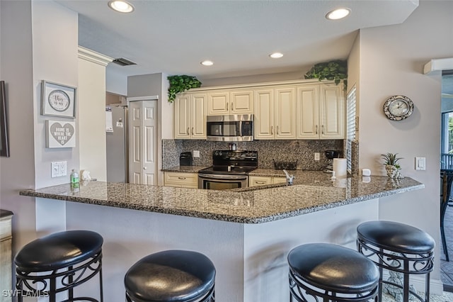 kitchen featuring visible vents, decorative backsplash, appliances with stainless steel finishes, dark stone countertops, and a peninsula