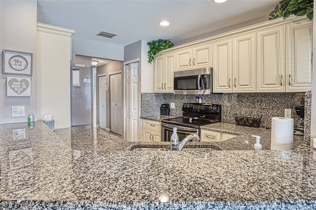 kitchen featuring cream cabinetry, electric range, kitchen peninsula, and dark stone counters