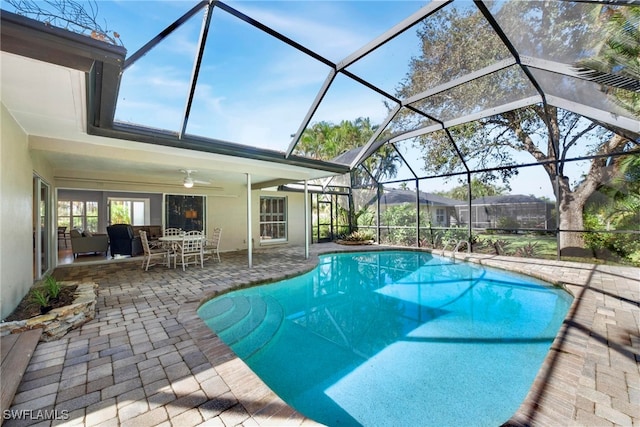 view of pool featuring a patio, glass enclosure, and ceiling fan