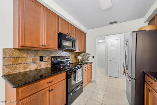 kitchen with decorative backsplash, dark stone countertops, black appliances, and light tile patterned floors