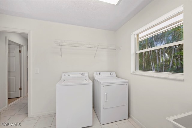 laundry area with independent washer and dryer, a textured ceiling, and light tile patterned floors