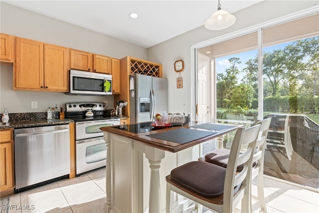 kitchen with appliances with stainless steel finishes, hanging light fixtures, and light tile patterned floors