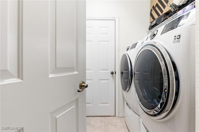 clothes washing area with light tile patterned flooring, separate washer and dryer, and laundry area