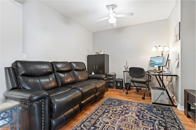 living area with baseboards, wood finished floors, and a ceiling fan