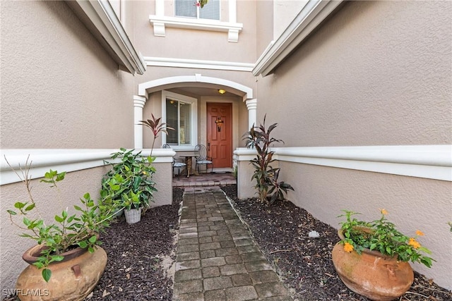entrance to property with covered porch and stucco siding