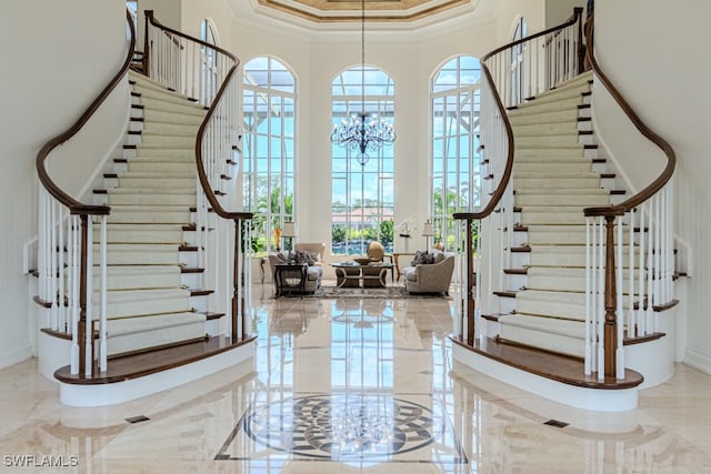 foyer featuring a towering ceiling, a chandelier, plenty of natural light, and crown molding