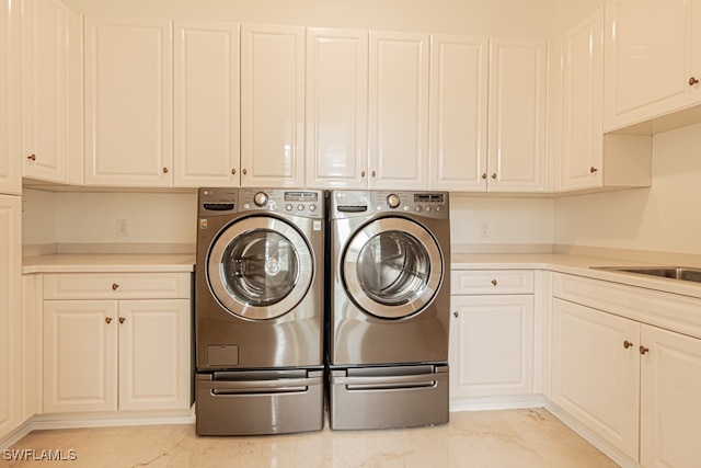 washroom featuring sink, washing machine and clothes dryer, and cabinets