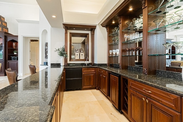 bar featuring dark stone counters, crown molding, and sink