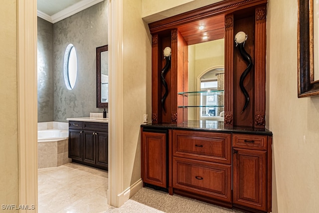 bathroom with tiled tub, vanity, ornamental molding, and a healthy amount of sunlight