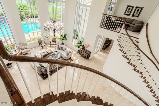 stairway featuring a notable chandelier and a towering ceiling