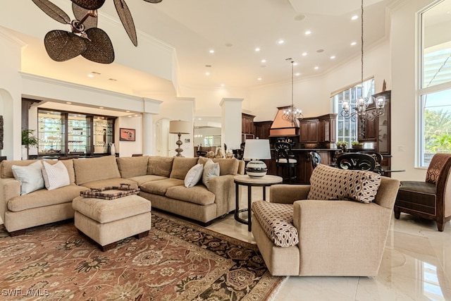 living room with ceiling fan with notable chandelier, a towering ceiling, and crown molding