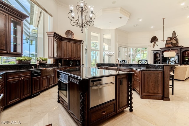 kitchen with pendant lighting, a notable chandelier, a kitchen island, a kitchen breakfast bar, and dark brown cabinetry