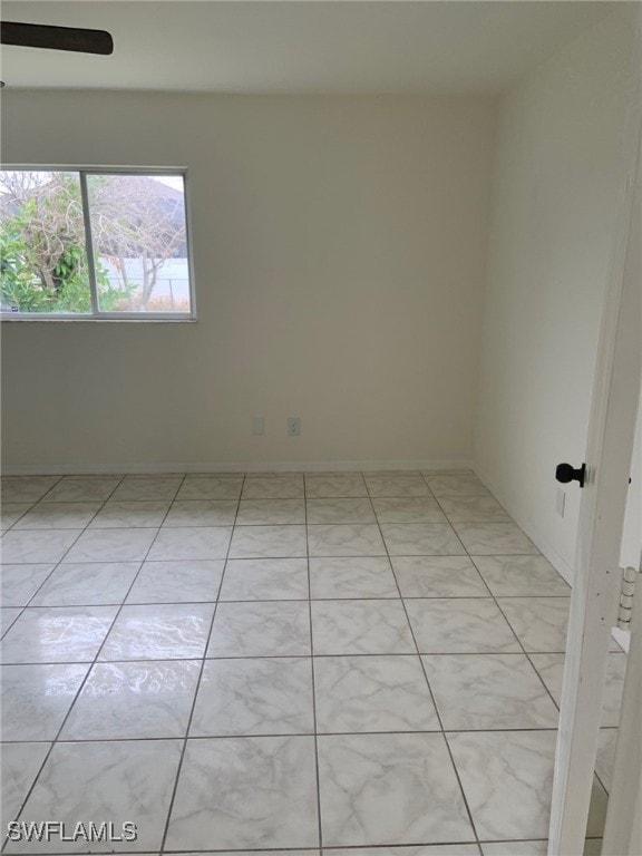 tiled empty room featuring ceiling fan