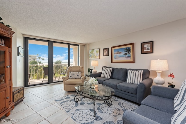 living room featuring a textured ceiling, a wall of windows, and light tile patterned flooring