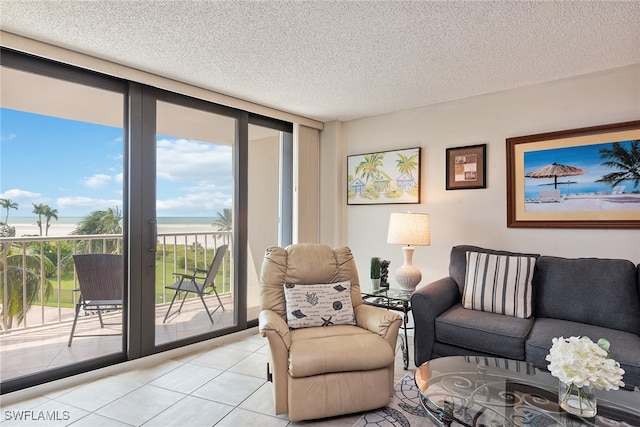 living room featuring floor to ceiling windows, a water view, a textured ceiling, and light tile patterned flooring