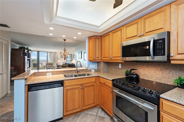 kitchen with sink, kitchen peninsula, tasteful backsplash, appliances with stainless steel finishes, and a tray ceiling