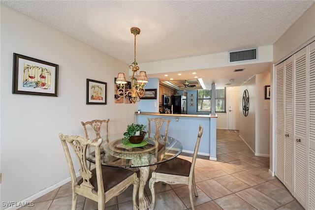 tiled dining space featuring a textured ceiling and an inviting chandelier