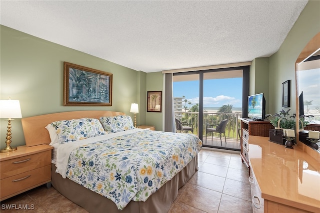 tiled bedroom featuring a textured ceiling, access to outside, and expansive windows