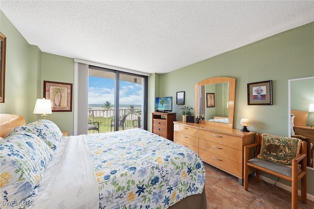 tiled bedroom featuring a textured ceiling, a wall of windows, and access to exterior