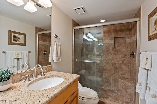 bathroom with a shower with shower door, vanity, and toilet