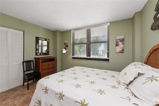 bedroom with a textured ceiling, a closet, and tile patterned floors