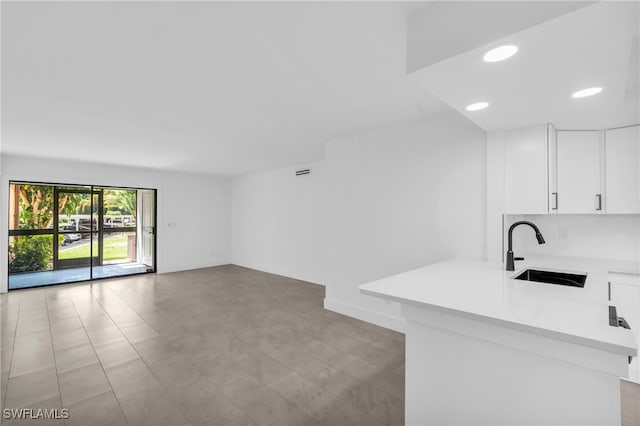 kitchen with white cabinetry, kitchen peninsula, and sink