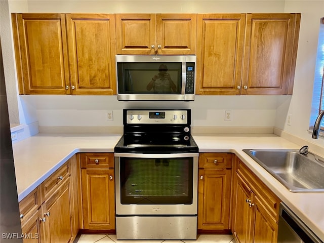 kitchen featuring appliances with stainless steel finishes, light tile patterned flooring, and sink