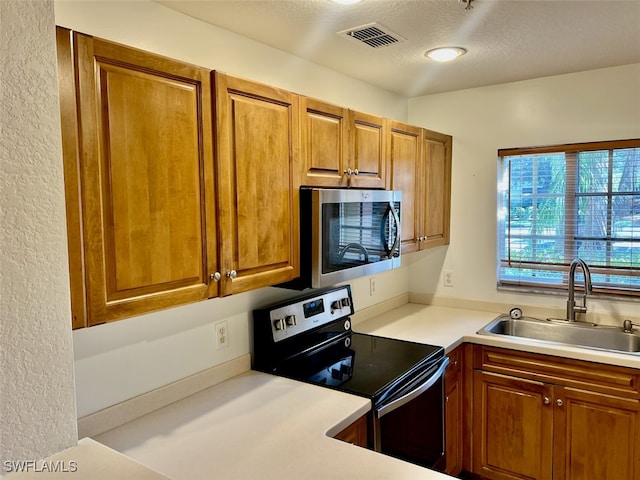 kitchen featuring electric stove, a textured ceiling, and sink