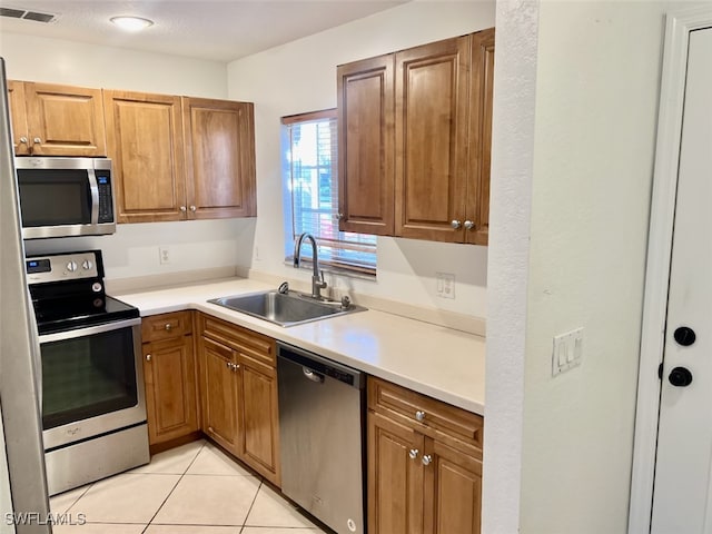 kitchen with stainless steel appliances, light tile patterned floors, and sink