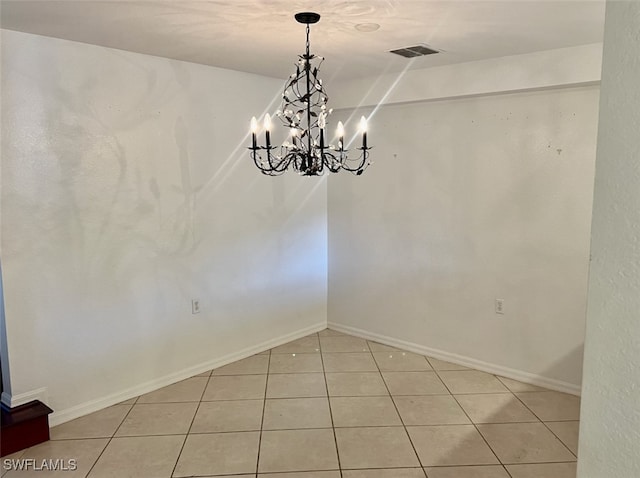 spare room with an inviting chandelier and light tile patterned floors