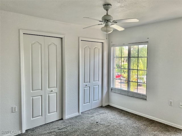 unfurnished bedroom featuring ceiling fan, multiple closets, and carpet floors