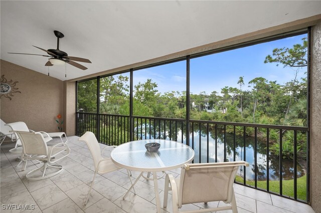 sunroom / solarium with a water view and ceiling fan