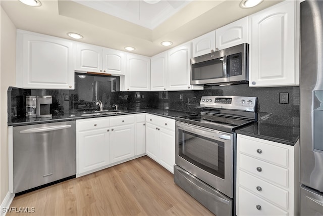 kitchen with appliances with stainless steel finishes, light hardwood / wood-style flooring, white cabinetry, and sink