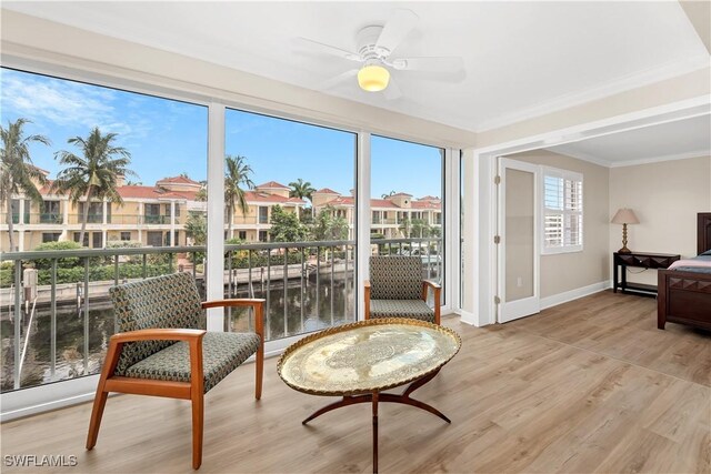 sitting room with ceiling fan, a water view, light wood-type flooring, and ornamental molding