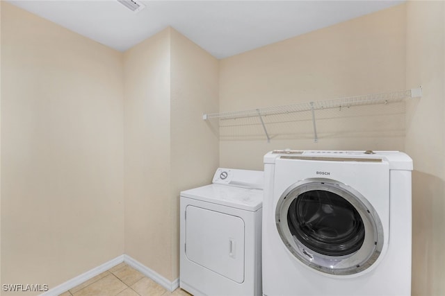 clothes washing area featuring separate washer and dryer and light tile patterned floors