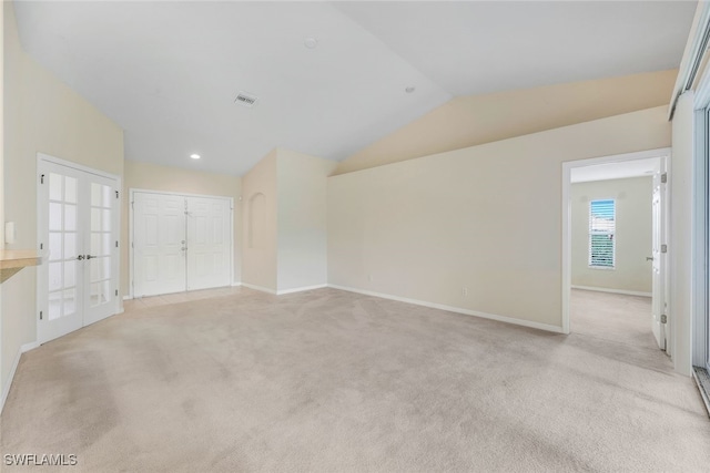 spare room with french doors, light carpet, and vaulted ceiling