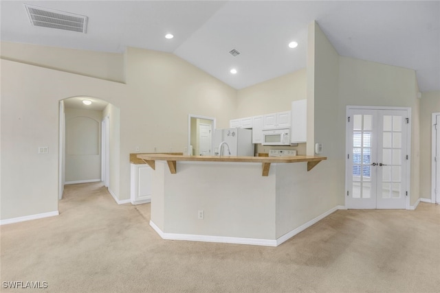 kitchen featuring a breakfast bar area, white cabinetry, kitchen peninsula, white appliances, and french doors